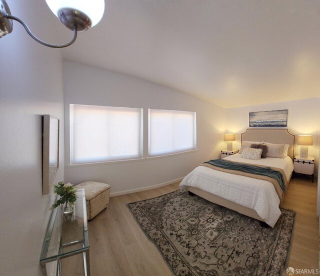 bedroom with lofted ceiling, multiple windows, and hardwood / wood-style floors