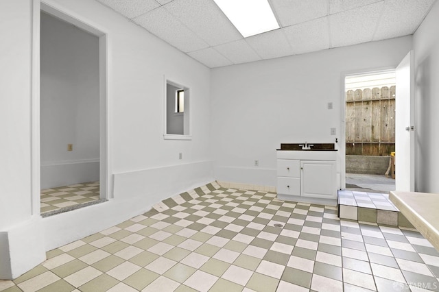 interior space featuring a paneled ceiling, vanity, and a bathing tub