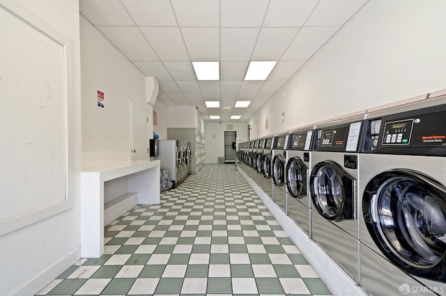 shared laundry area featuring washing machine and clothes dryer, light floors, and baseboards