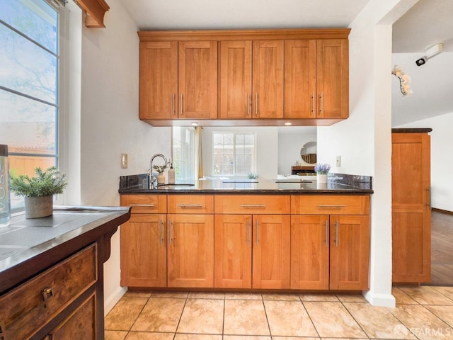 1113 Pebblewood Way, San Mateo, CA 94403 - kitchen featuring dark stone counters, a healthy amount of sunlight, and brown cabinets