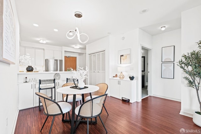 dining room with dark wood-type flooring, an inviting chandelier, and baseboards