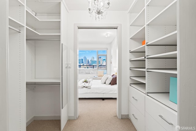 spacious closet featuring an inviting chandelier and light colored carpet