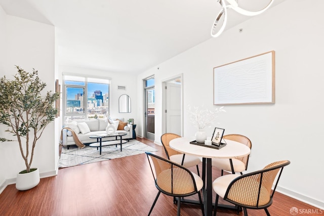 dining room with a city view, baseboards, and wood finished floors