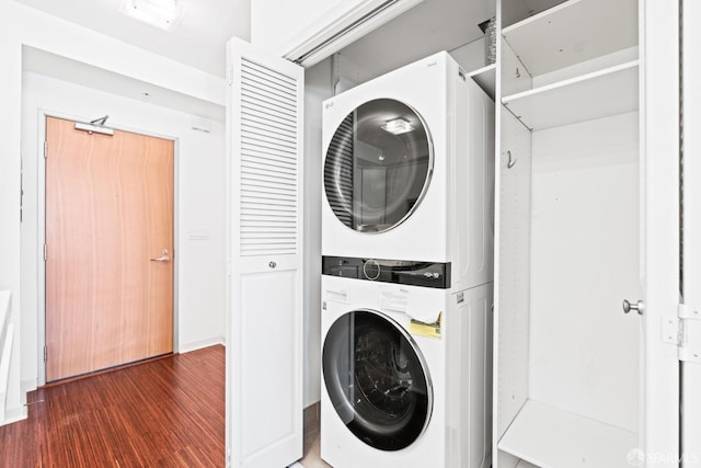 clothes washing area with laundry area, stacked washing maching and dryer, and wood finished floors