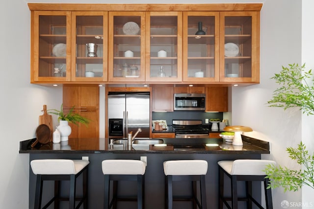351 Buena Vista E Avenue 604E, San Francisco, CA 94117 - kitchen with appliances with stainless steel finishes, a peninsula, glass insert cabinets, brown cabinets, and a kitchen breakfast bar