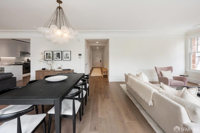 dining area with crown molding, wood finished floors, a chandelier, and baseboards