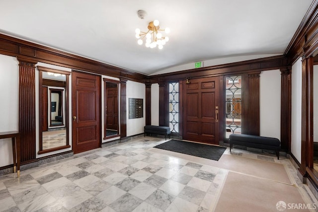 entrance foyer with a chandelier, ornate columns, and vaulted ceiling