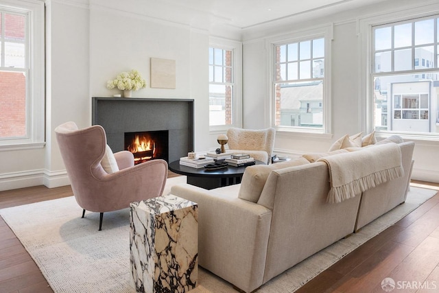 living room with wood finished floors, a lit fireplace, and baseboards