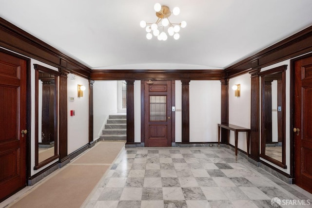 foyer with ornate columns, a chandelier, vaulted ceiling, and stairs