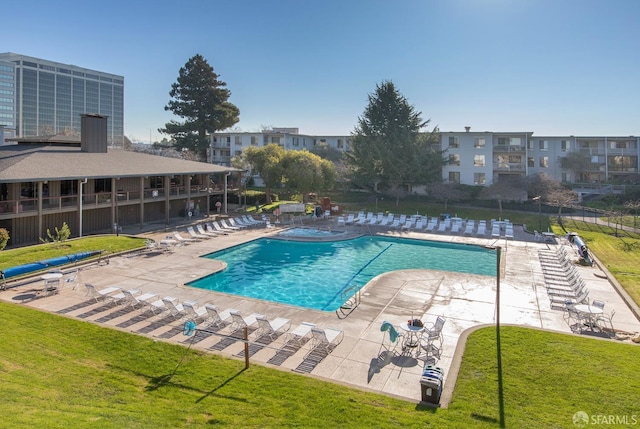 view of pool with a community hot tub, a patio area, and a lawn