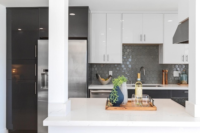 kitchen with tasteful backsplash, light stone countertops, sink, and white cabinets