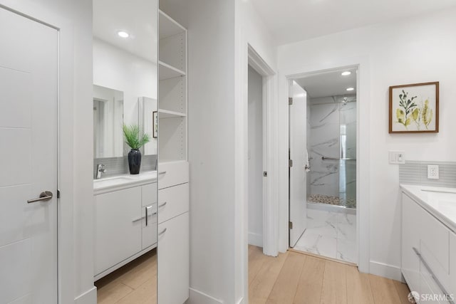 bathroom featuring tiled shower, wood-type flooring, vanity, and backsplash