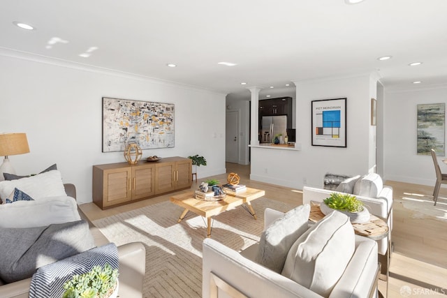 living room featuring light hardwood / wood-style floors, crown molding, and decorative columns