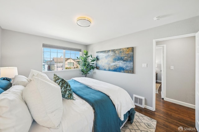 bedroom with baseboards, visible vents, and wood finished floors