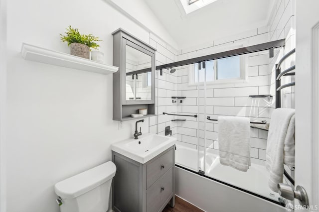 bathroom with enclosed tub / shower combo, toilet, vanity, and vaulted ceiling with skylight