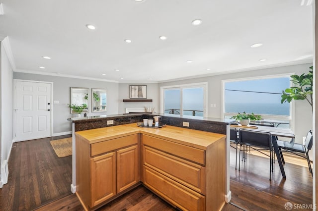 kitchen with crown molding, a center island, wood counters, recessed lighting, and dark wood-style flooring