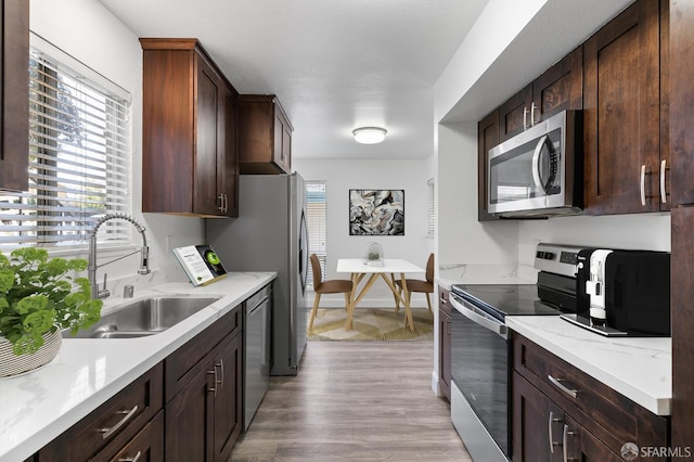 kitchen with light stone counters, stainless steel appliances, sink, and a wealth of natural light