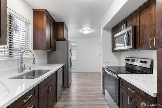 kitchen featuring light stone counters, appliances with stainless steel finishes, sink, and plenty of natural light