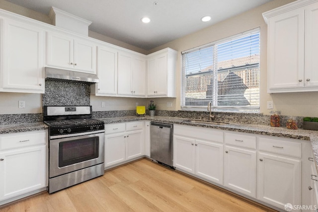 kitchen with sink, stainless steel appliances, white cabinetry, and light wood-type flooring