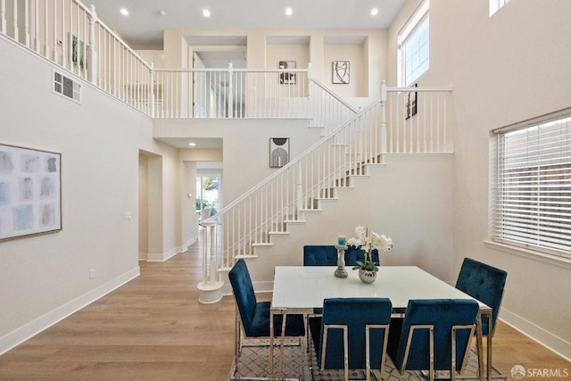 dining space featuring a towering ceiling and light hardwood / wood-style floors