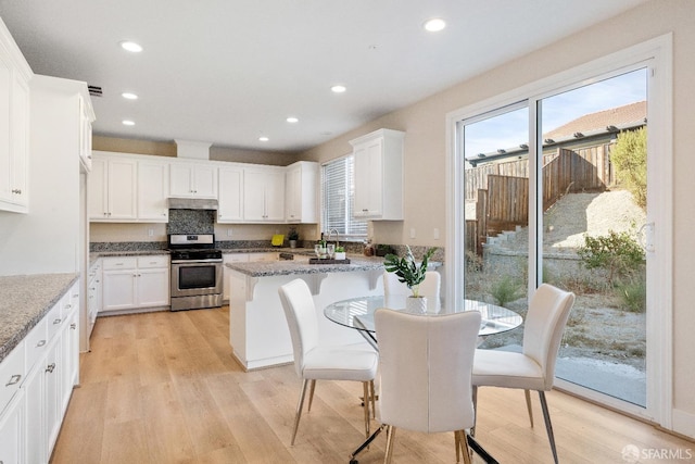 kitchen featuring stainless steel stove, dark stone countertops, light hardwood / wood-style floors, and white cabinetry