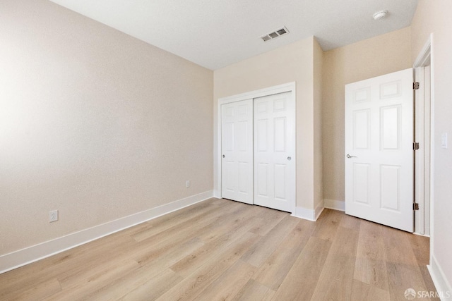 unfurnished bedroom featuring a closet and light wood-type flooring