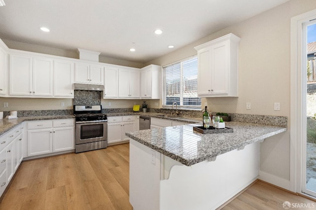 kitchen featuring white cabinets, light wood-type flooring, kitchen peninsula, and appliances with stainless steel finishes