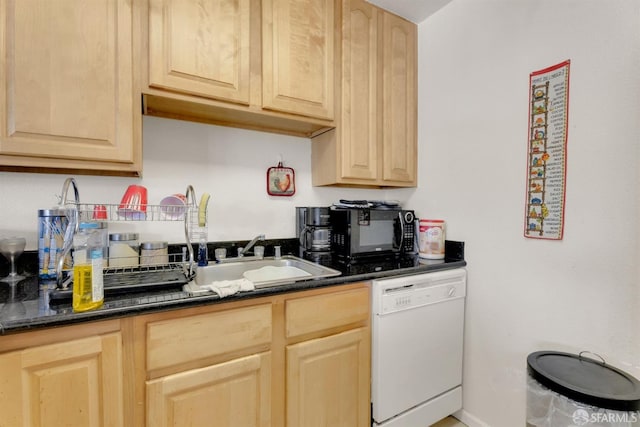 kitchen featuring white dishwasher, light brown cabinetry, dark stone countertops, and sink