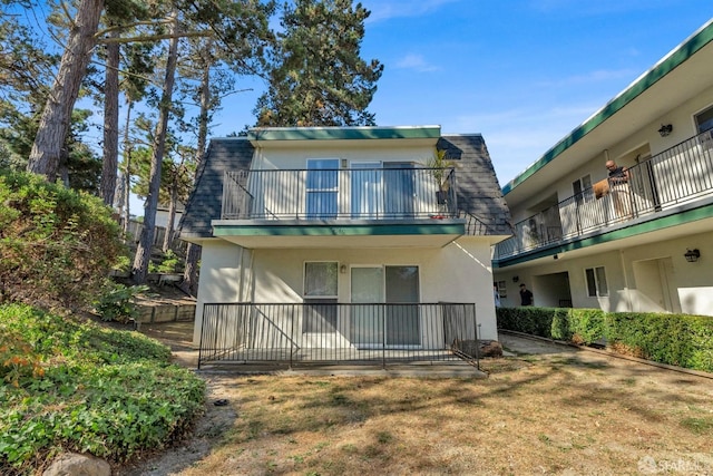 back of house featuring a balcony and a lawn