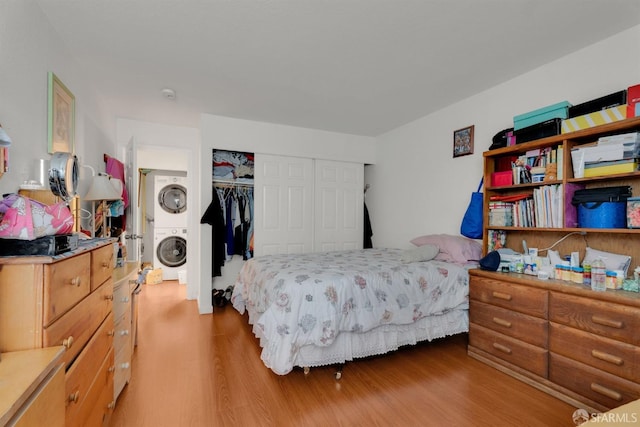 bedroom featuring wood-type flooring, a closet, and stacked washing maching and dryer