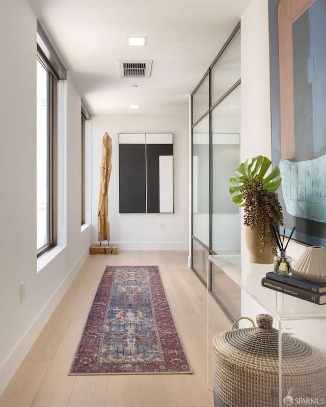 hallway with plenty of natural light and light hardwood / wood-style flooring