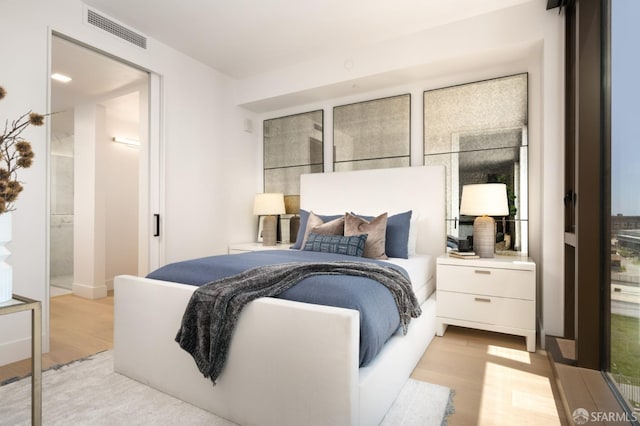 bedroom featuring connected bathroom and light wood-type flooring