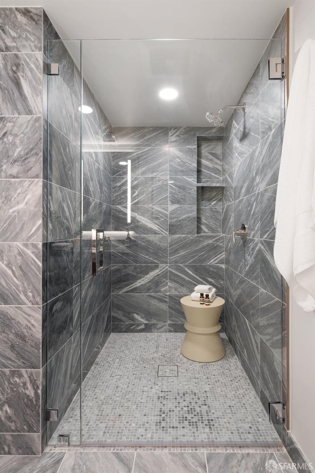 bathroom with tile walls, toilet, and an enclosed shower