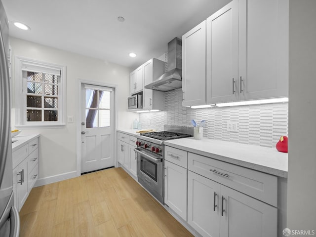 1624 Vallejo St Unit 2, San Francisco, CA 94123 - kitchen with wall chimney range hood, appliances with stainless steel finishes, light wood-style floors, backsplash, and light countertops