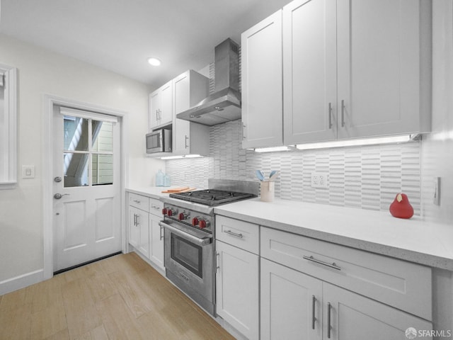 1624 Vallejo St Unit 2, San Francisco, CA 94123 - kitchen with wall chimney exhaust hood, stainless steel appliances, light countertops, white cabinetry, and recessed lighting