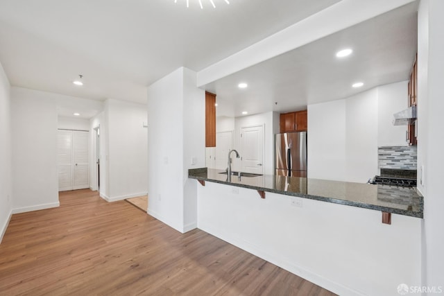 423 7th St Unit 303, Oakland, CA 94607 - kitchen with freestanding refrigerator, under cabinet range hood, a peninsula, light wood-style flooring, and recessed lighting