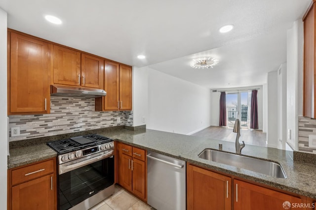 423 7th St Unit 303, Oakland, CA 94607 - kitchen featuring appliances with stainless steel finishes, under cabinet range hood, brown cabinets, dark stone counters, and recessed lighting