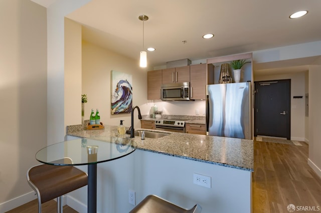55 Page St Unit 428, San Francisco, CA 94102 - kitchen featuring appliances with stainless steel finishes, a sink, a peninsula, baseboards, and wood finished floors