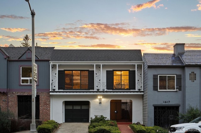 townhome / multi-family property featuring an attached garage, stucco siding, a balcony, and a chimney