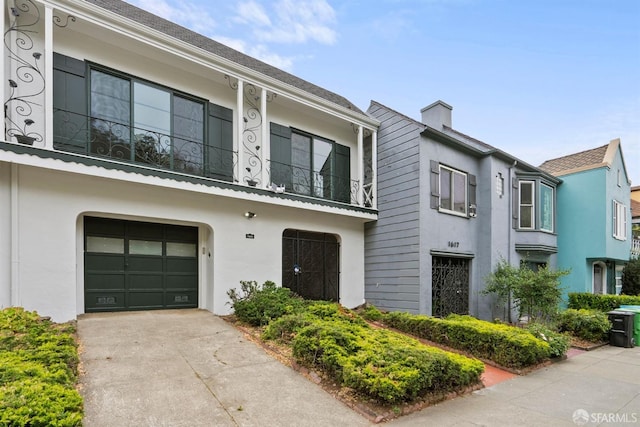 multi unit property featuring stucco siding, a garage, concrete driveway, and a chimney