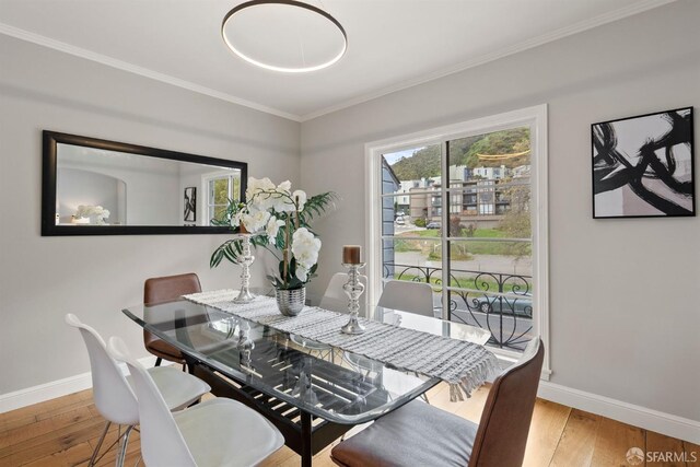 dining room featuring baseboards, hardwood / wood-style floors, and crown molding