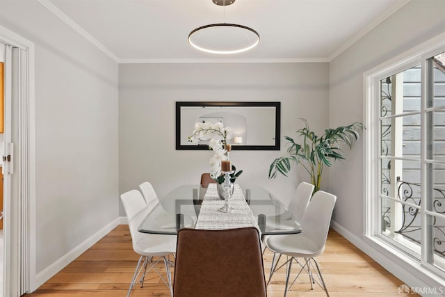 dining space featuring light wood-type flooring, crown molding, and baseboards
