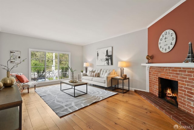 living room with a fireplace, hardwood / wood-style flooring, baseboards, and crown molding