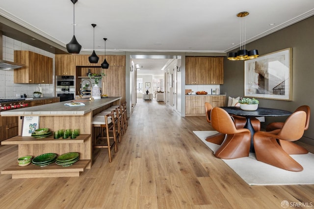 kitchen featuring sink, light hardwood / wood-style floors, decorative light fixtures, and backsplash