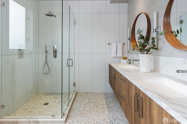 bathroom with tile walls, a shower with door, and vanity