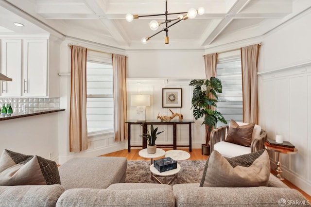 living area with light wood-type flooring, beam ceiling, a chandelier, and coffered ceiling