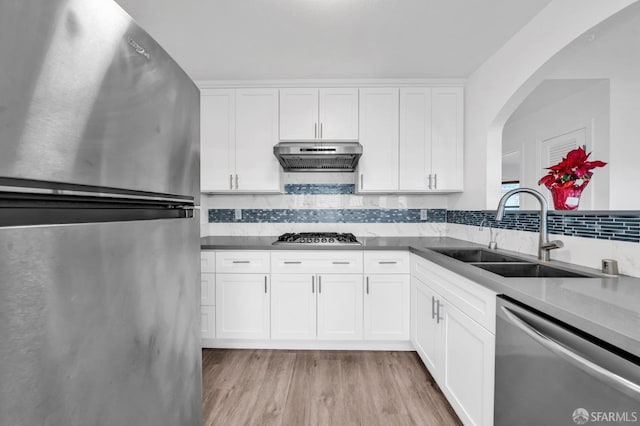 kitchen featuring white cabinets, stainless steel appliances, tasteful backsplash, sink, and light wood-type flooring