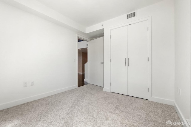 unfurnished bedroom with light carpet and a closet