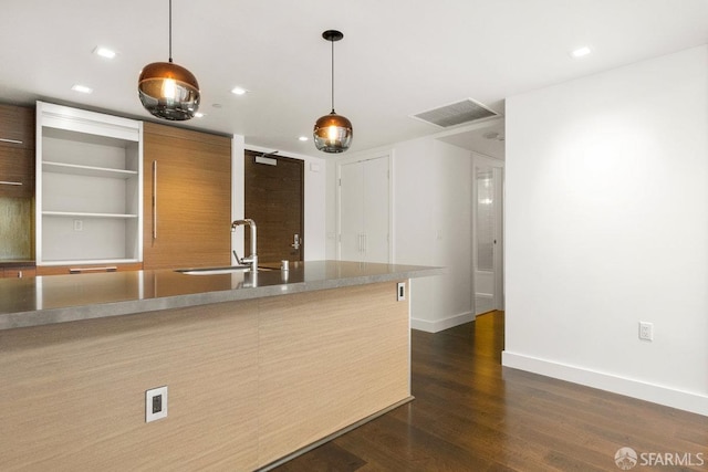 kitchen featuring hanging light fixtures, dark wood-type flooring, and sink