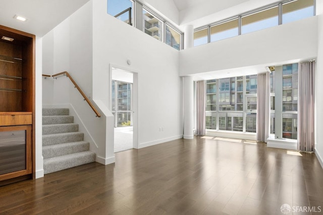 unfurnished living room featuring dark hardwood / wood-style floors and a high ceiling